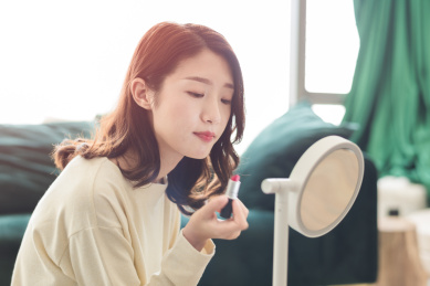 年轻女性在梳妆镜前涂口红