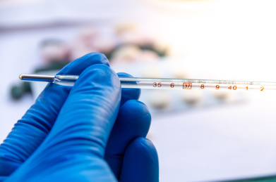 一只手戴蓝色胶手套拿温度计