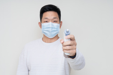 戴口罩的中国男人使用电子体温计