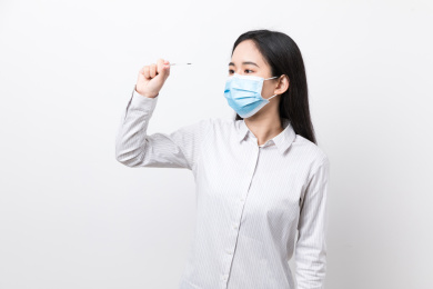 戴着口罩的女生使用体温计测量体温