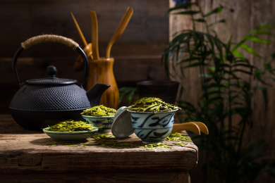放在木桌上用复古碗碟装龙井干茶叶和茶具