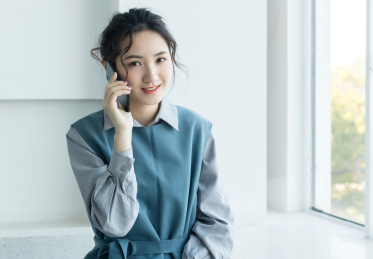 坐在窗边打电话的年轻女性