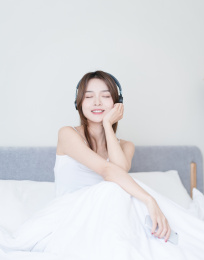 漂亮的女生坐在床上闭着眼睛听音乐