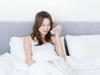 女生坐在床上使用手机