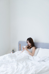 女生坐在床上使用手机
