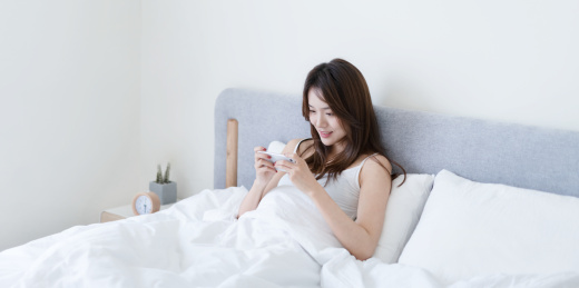 女生坐在床上使用手机