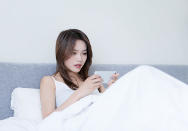 女生坐在床上使用手机