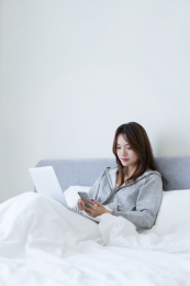 女生坐在床上看手机