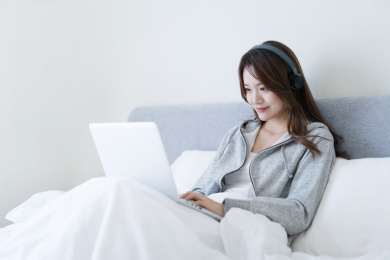 女生坐在床上戴着耳机