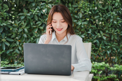 商务女性肖像对着记本电脑使用手机通话