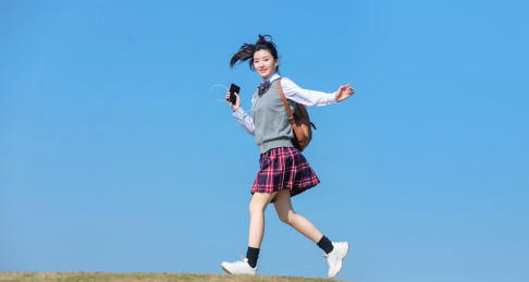  蓝色天空背景下，正在慢跑的亚洲女学生