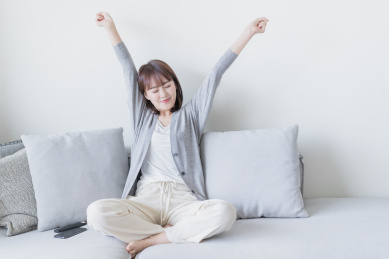 女生盘腿坐在沙发上闭眼双手伸懒腰