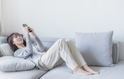 女生躺在沙发上用双手玩手机