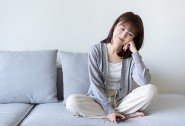 年轻的亚洲女生盘腿坐在沙发上