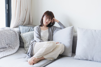 年轻的亚洲女生闭眼靠在沙发上扶着头休息