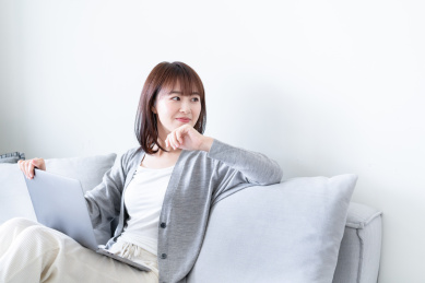 女生坐在沙发上一边看电脑一边思考