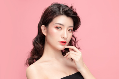 粉色背景里的亚洲美女面部特写，化妆护肤整