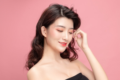 粉色背景里的亚洲美女面部特写，化妆护肤整