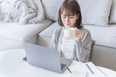 女生在家一边看电脑一边喝水