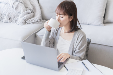 女生在家一边看电脑一边喝水