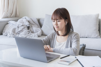 女生坐在客厅带着耳机办公 上网课