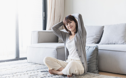 女生盘腿坐在客厅地毯上双手放于脑后