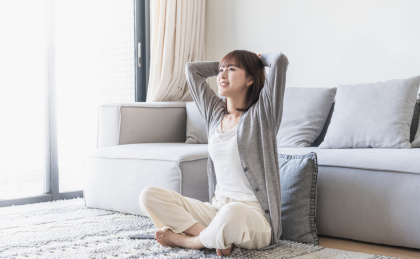 女生盘腿坐在客厅地毯上双手放于脑后