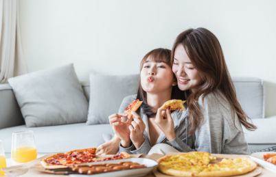 两位年轻亚洲女孩在客厅吃披萨