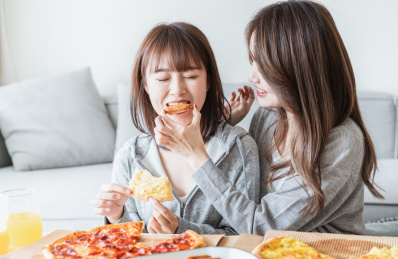 两位年轻亚洲女孩在客厅吃披萨