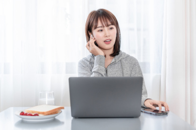 年轻女性一边吃早餐一边工作接电话