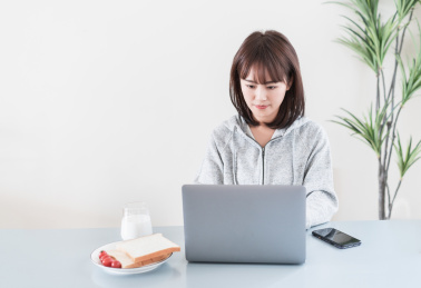 年轻女性一边看电脑一边吃早餐