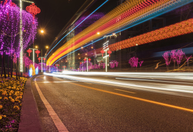 春节公路上挂满彩灯，汽车在公路上的光影轨