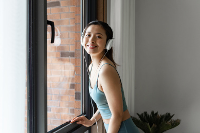 一位年轻的亚洲女性在窗边听音乐