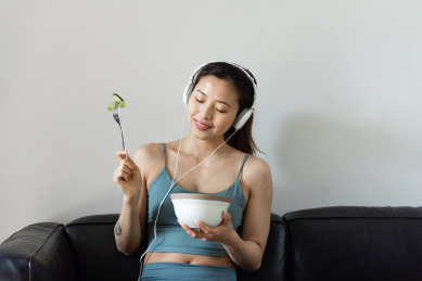 一位年轻的亚洲女性在客厅吃健康的蔬菜沙拉