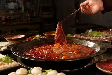 筷子夹着毛肚正在沸腾的麻辣火锅烫着