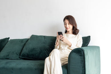 年轻女士在客厅使用智能手机玩游戏