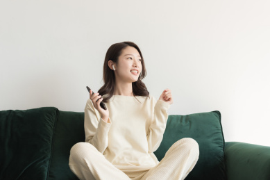 一名年轻女性在客厅里使用无线耳机听音乐