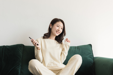 一名年轻女性在客厅里使用无线耳机听音乐