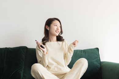 一名年轻女性在客厅里使用无线耳机听音乐