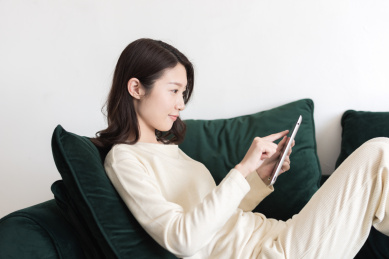 年轻女性坐在沙发上使用平板电脑