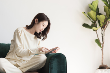 年轻女性坐在沙发上使用平板电脑