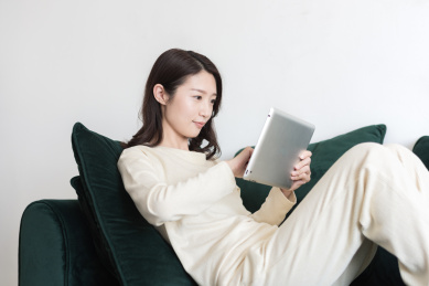 年轻女性坐在沙发上使用平板电脑