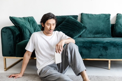 客厅里一名年轻男性拿着手机在思考