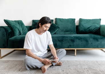 客厅里一名年轻男性拿着手机在思考