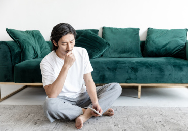 客厅里一名年轻男性拿着手机在思考