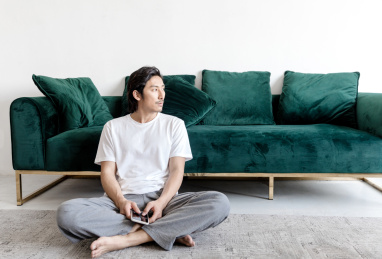 客厅里一名年轻男性拿着手机在思考