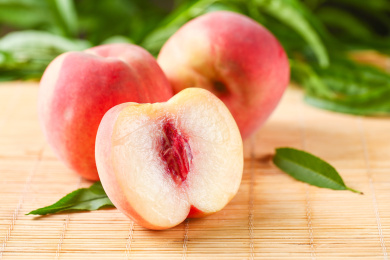 竹垫子上放着春雪水蜜桃和水蜜桃果肉 