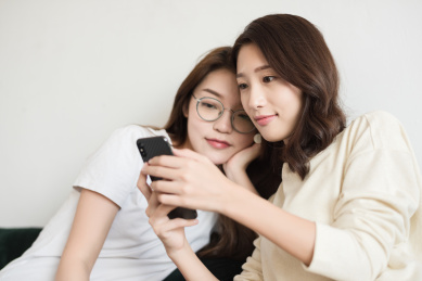 客厅沙发上两个年轻女性在玩手机