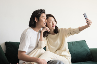 年轻情侣坐在沙发上用手机自拍