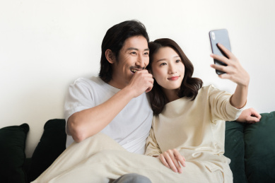 年轻情侣坐在沙发上用手机自拍